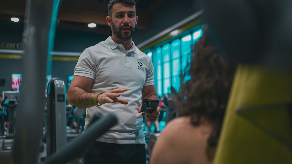 Sesión de entrenamiento en el gimnasio con un entrenador personal, enfocada en el rendimiento y el bienestar físico.